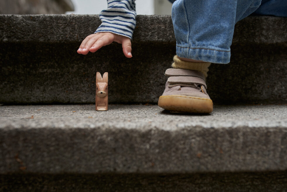 Kinderhand greift nach Holztier