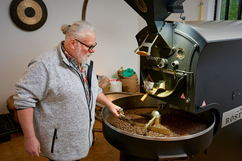 Kaffeeröster begutachtet den gerösteten Kaffee an das Röstmaschine stehend