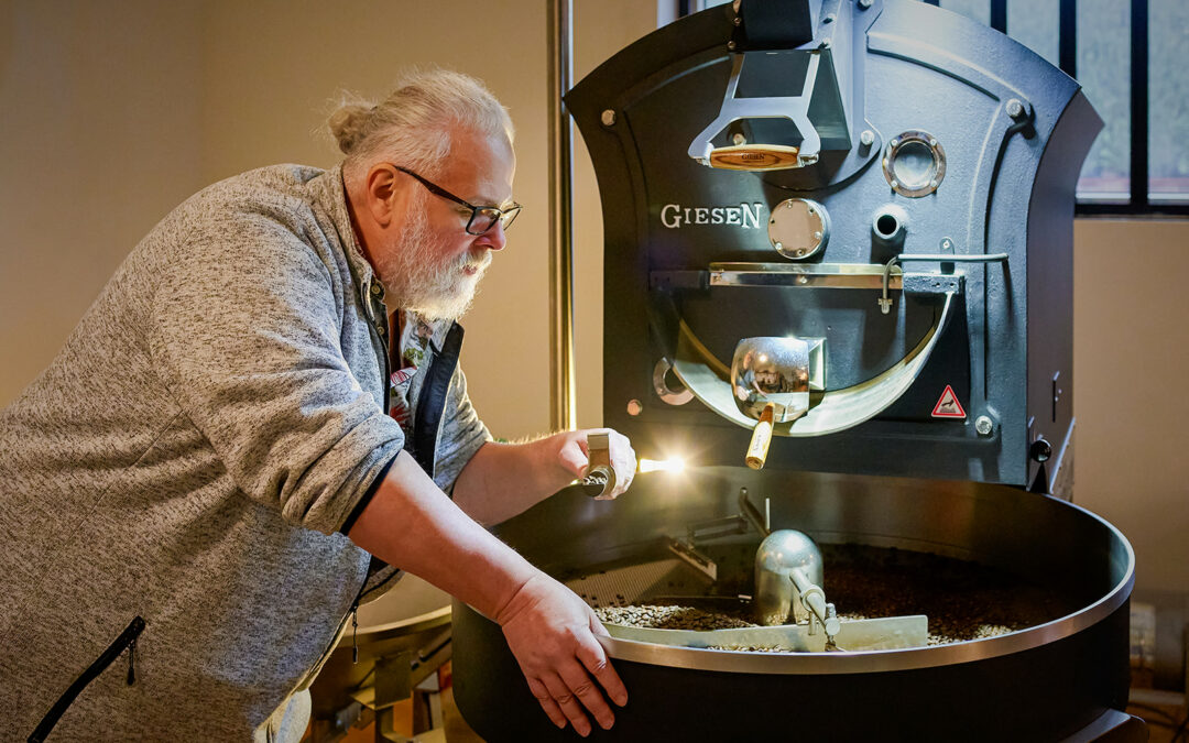 Kaffeeröster steht an seiner Köstmaschine und prüft den gerösteten Kaffee